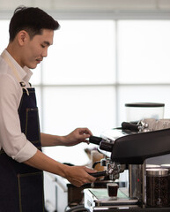 Asian young making a cup of coffee in a coffee machine, the steam and the cup. Espresso maker machine with portafilter close up. Concept Coffee maker in cafe.