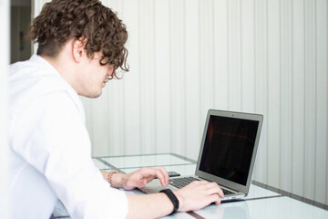 Caucasian man with curly hair working at the laptop. copy space. side view. horizontal.