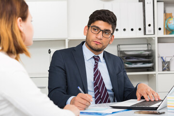 Positive businessman welcoming female client at workplace in office