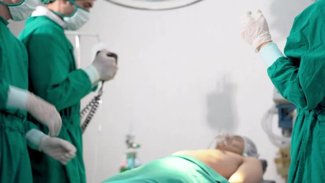 close up hands doctor using heat pump and Electrical cardioversion while Emergency heart pulse drop. professional surgeons operating a surgery human chest body in operating room at Hospital.