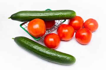Fresh tomatoes and cucumbers in a metal basket of a supermarket