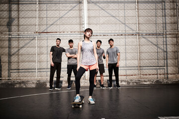 young asian female skateboarder and her male friends