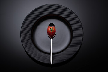 Tomato on a spoon with dark background 