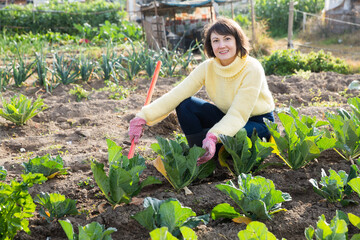 Portrait of smiling young woman working in garden at spring farm