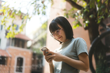 Young adult happy asian woman wear eyeglasses using mobile phone for social media.