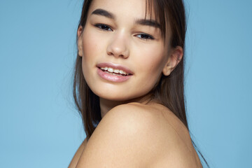 Obraz premium Woman with naked shoulders long hair cosmetics attractive look blue background