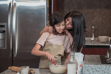 Mexican mother teaching  her daughter to cook in the kitchen