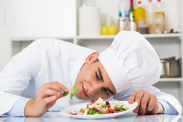 Obraz na płótnie Canvas Young man is degustating salad on kitchen.