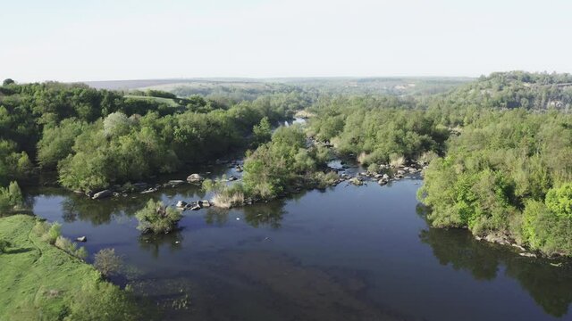 Wild river drone footage. Green trees and many rocks in the water.