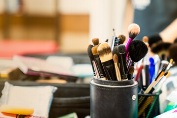 An image of a makeup tool like a face brush is placed in a black cylinder placed on a dresser with a blurred background.