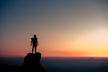 Silhouette of traveler or hiker on background of sunset sky