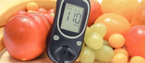 Glucose meter with sugar level and fresh fruits. Healthy eating during diabetes