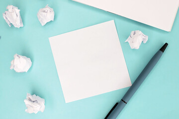 On a turquoise background next to a pen and crumpled sheets of paper there is a clean white sheet. Template