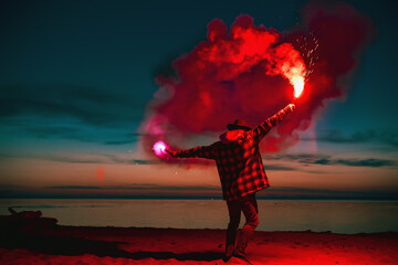 Man goes with torch fire at sunset beach - obrazy, fototapety, plakaty