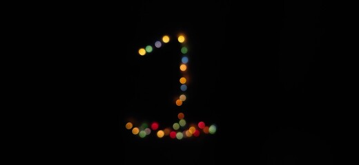 Closeup of Number (1) made with multicolored blurred bokeh Christmas lights in a isolated black background with copy space