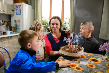 Children blow out candles on a name cake, a delicious dessert for a birthday, bright and colorful candles.