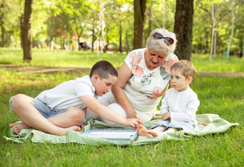 Grandma and grandchildren. Two generations of family. Young boys and grandmother sitting in sunny...