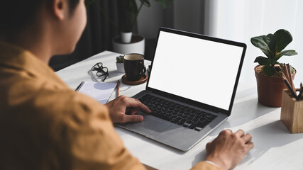 Rear view young man using computer laptop while sitting in comfortable home.