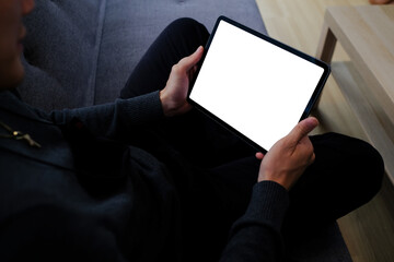 Young man sitting on cozy sofa and using digital tablet.