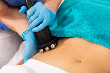 Fototapeta premium Closeup of hardware procedure of rf skin lifting on female belly in aesthetic cosmetology clinic