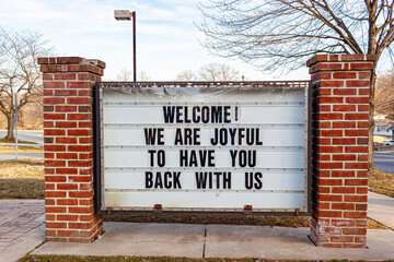 A large notice board in front of a public school in Maryland has a message to students who have been away due to COVID-19 pandemic. It reads welcome, we are joyful to have you back with us.