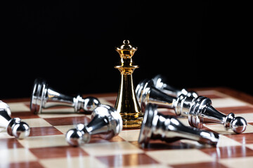 Gold queen chess defeats silver figures on board.