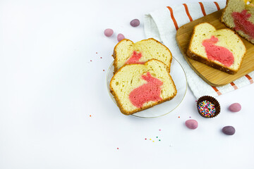 Funny Easter cake with pink bunny in a cut. Traditional Easter baking and chocolate eggs on white background. Delicious breakfast, traditional tea time treat,copy space 