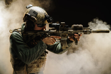 Special forces soldier aiming with his rifle in fog