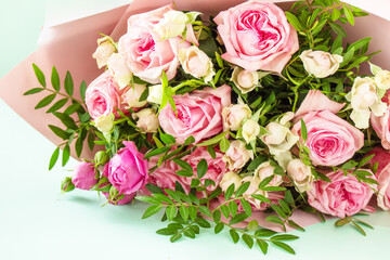 Mother's day, womens day or birthday greetings concept. Beautiful bouquet of blooming delicate pink roses and spring greenery on a green background. Copy space.