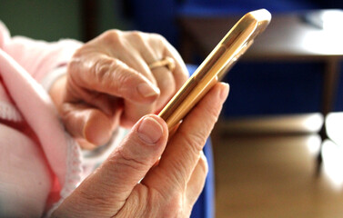 Close up view of old woman hand using smartphone, touching screen 