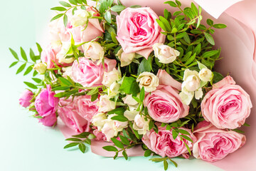 Mothers day, womens day or birthday greetings concept. Beautiful bouquet of blooming delicate pink roses and spring greenery on a green background.