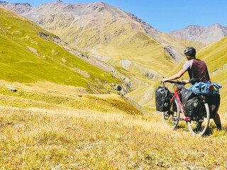 Back view cyclist push touring bicycle uphill to mountain. Atsunta pass trekking route on bicycle