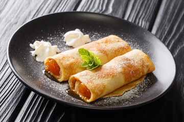 Austrian breakfast Palatschinken Apricot crepes with powdered sugar close-up in a plate on the table. horizontal
