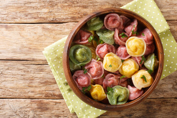 Cooked multi-colored tortellini dumplings close-up in a bowl on the table. horizontal top view from above