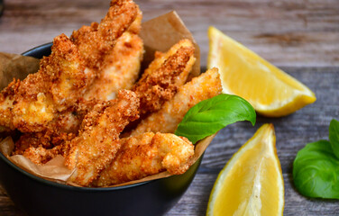 
 Crispy  deep fried home made    chicken strips Breaded  with  almond flour chicken  breast fillets  with chilly peppers and fresh   basil on wooden rustic background. Ketogenic diet food