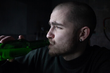 A photo of a young depressed drunk man drinking beer from a bottle, at home, brooding and confused, like an alcoholic, suffering from the problem of alcoholism and alcohol addiction