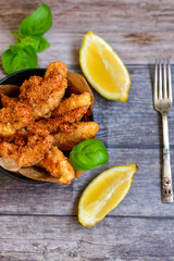 
 Crispy  deep fried home made    chicken strips Breaded  with  almond flour chicken  breast fillets  with chilly peppers and fresh   basil on wooden rustic background. Ketogenic diet food