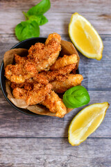 
 Crispy  deep fried home made    chicken strips Breaded  with  almond flour chicken  breast fillets  with chilly peppers and fresh   basil on wooden rustic background. Ketogenic diet food