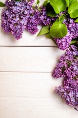 A bouquet of lilacs lies on a white wooden background

