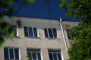 A city wall with windows in a building with apartments for rent. A rainwater downpipe is on the wall outside. High quality photo