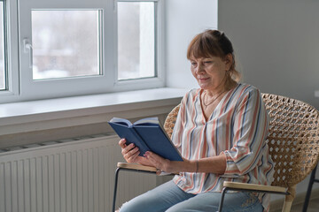 Senior woman at home reading book. smiling older person enjoying reading books. retirment home care