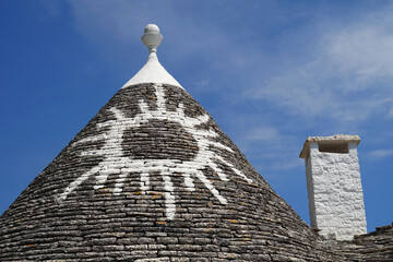 Trullo conical house with white symbol and top pinnacle stone and chimney