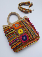 Image of colorful crochet bag made of leftover yarn. Isolated against white surface. Concept of creativity, something bright colorful, and utilization leftover things. Strap also appeared in frame. 