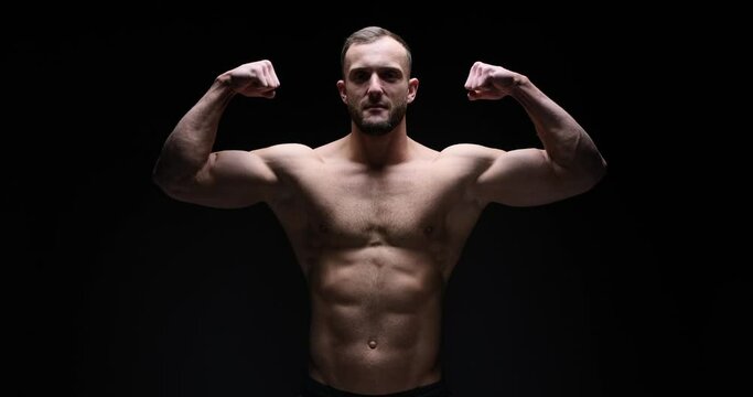Shirtless muscular man flexing biceps over black background