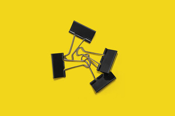 pile of black paper clips on a yellow background