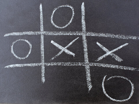 The tic tac toe game on blackboard with chalk grid, naughts and crosses - Powered by Adobe