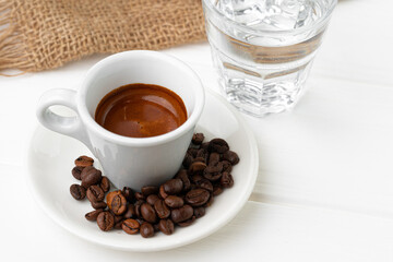 Cup of espresso with glass of water on white table