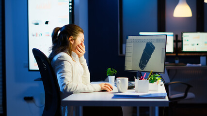 Tired designer engineer analizing new prototype of 3D model of the plant yawning working overtime....