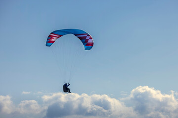 Paraglider flying over the mountains. Active people enjoying in extreme and adrenalin sports.