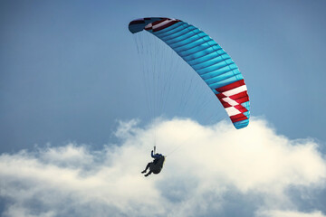 Paraglider flying over the mountains. Active people enjoying in extreme and adrenalin sports.